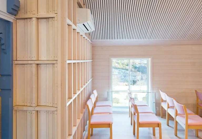 Lyst og åpent rom med elegant listverk på trepanelvegger og tak, samt oransje stoler som tilfører en varm fargekontrast.