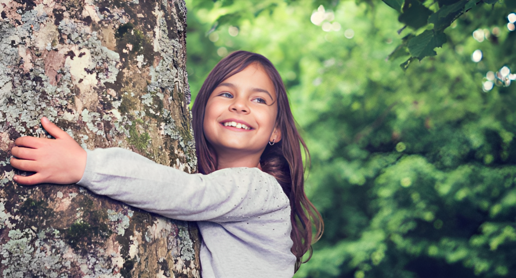 Et smilende barn omfavner et tre, illustrerende Thaugland AS sitt engasjement for bærekraft og natur som har gjort dem til proffenes valg i over 100 år.